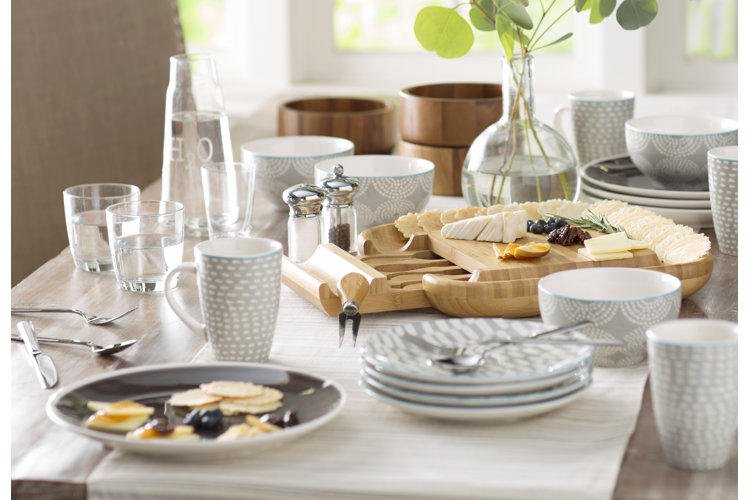 cheese board at the center of stacks of dishware