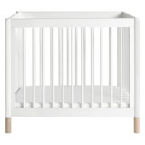 white crib with natural wood legs